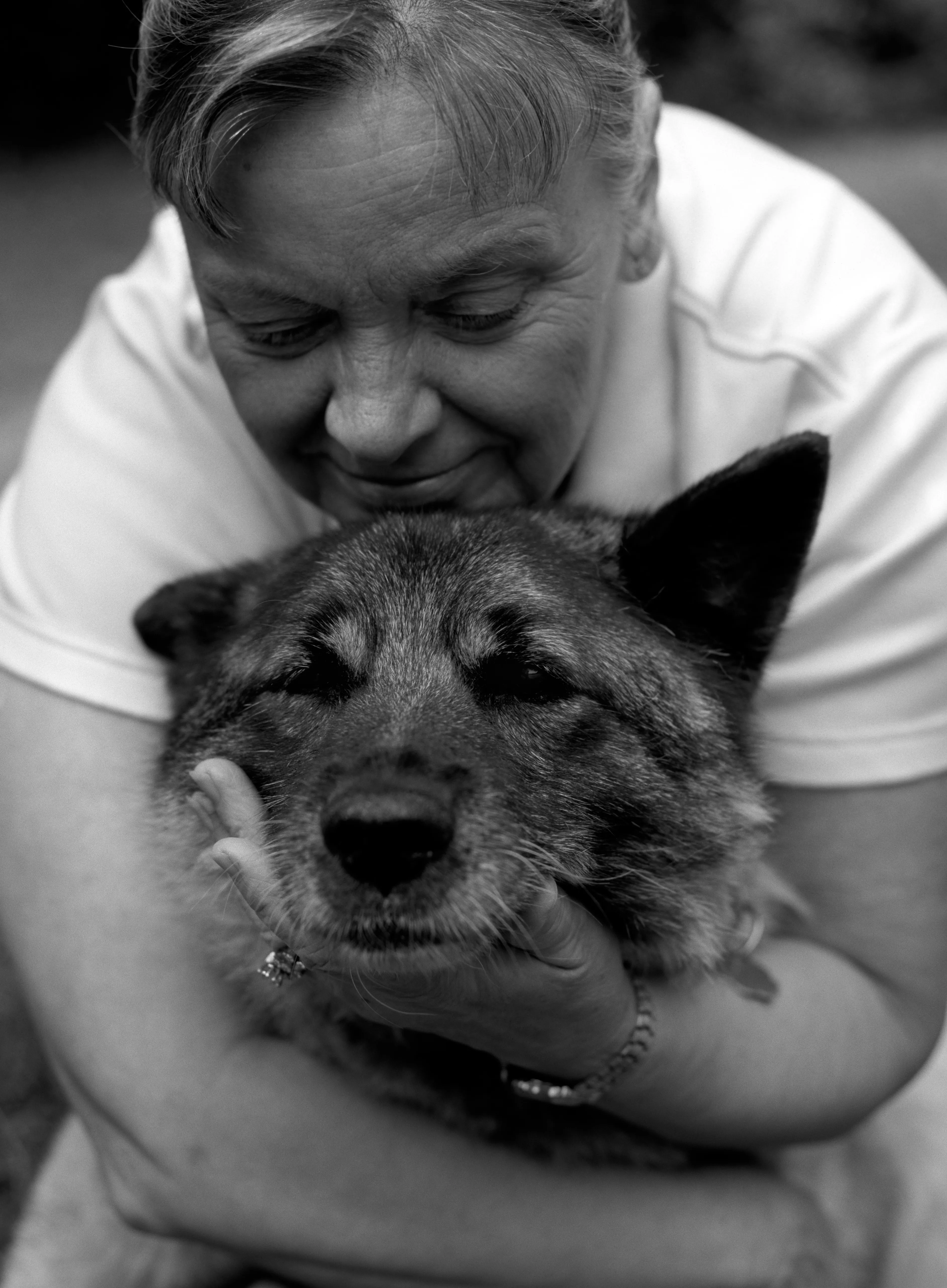 Brenda lowering her face to the top of Marilla's head, the elkhound looking towards the camera. Black and white.