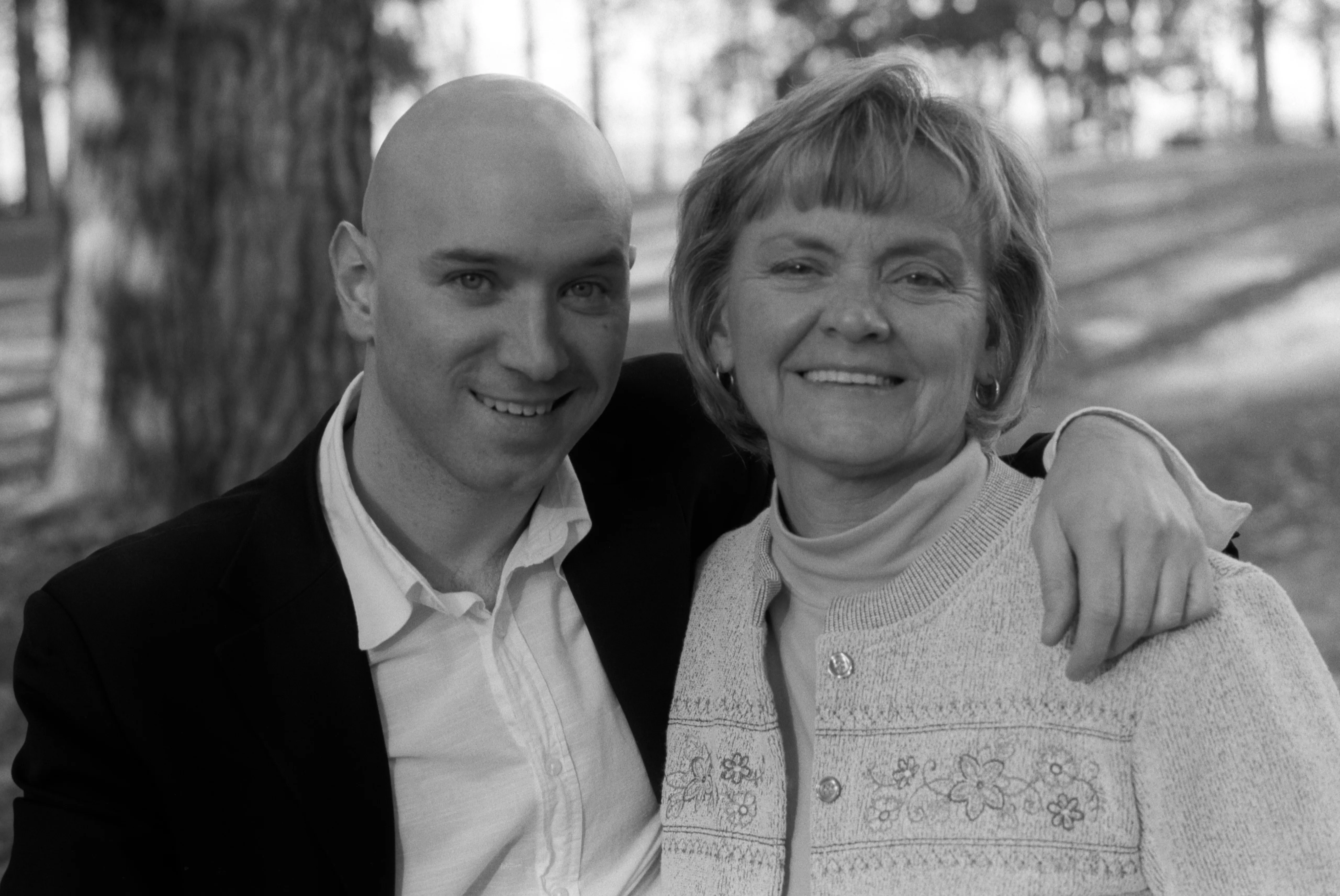 Brenda with her son, the two of them side by side in dark clothing against a plain background. Black and white.