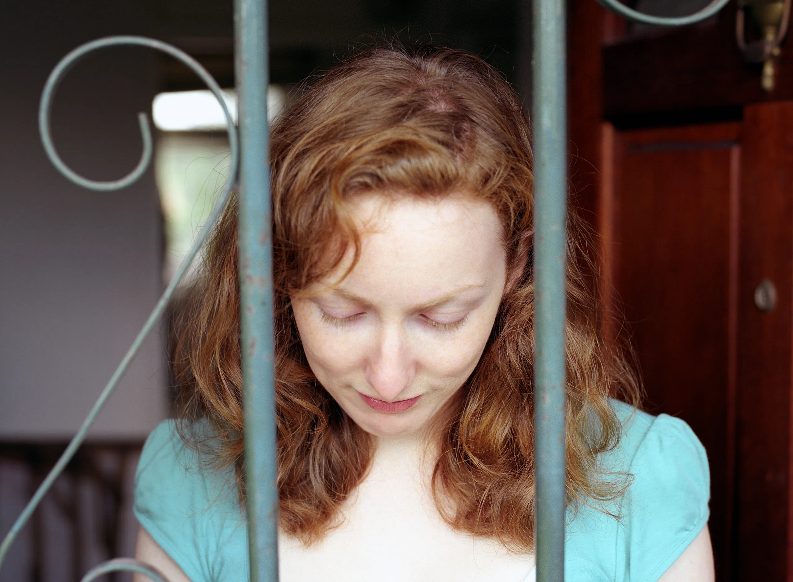 Catherine behind a wrought-iron railing, head bowed, eyes closed.