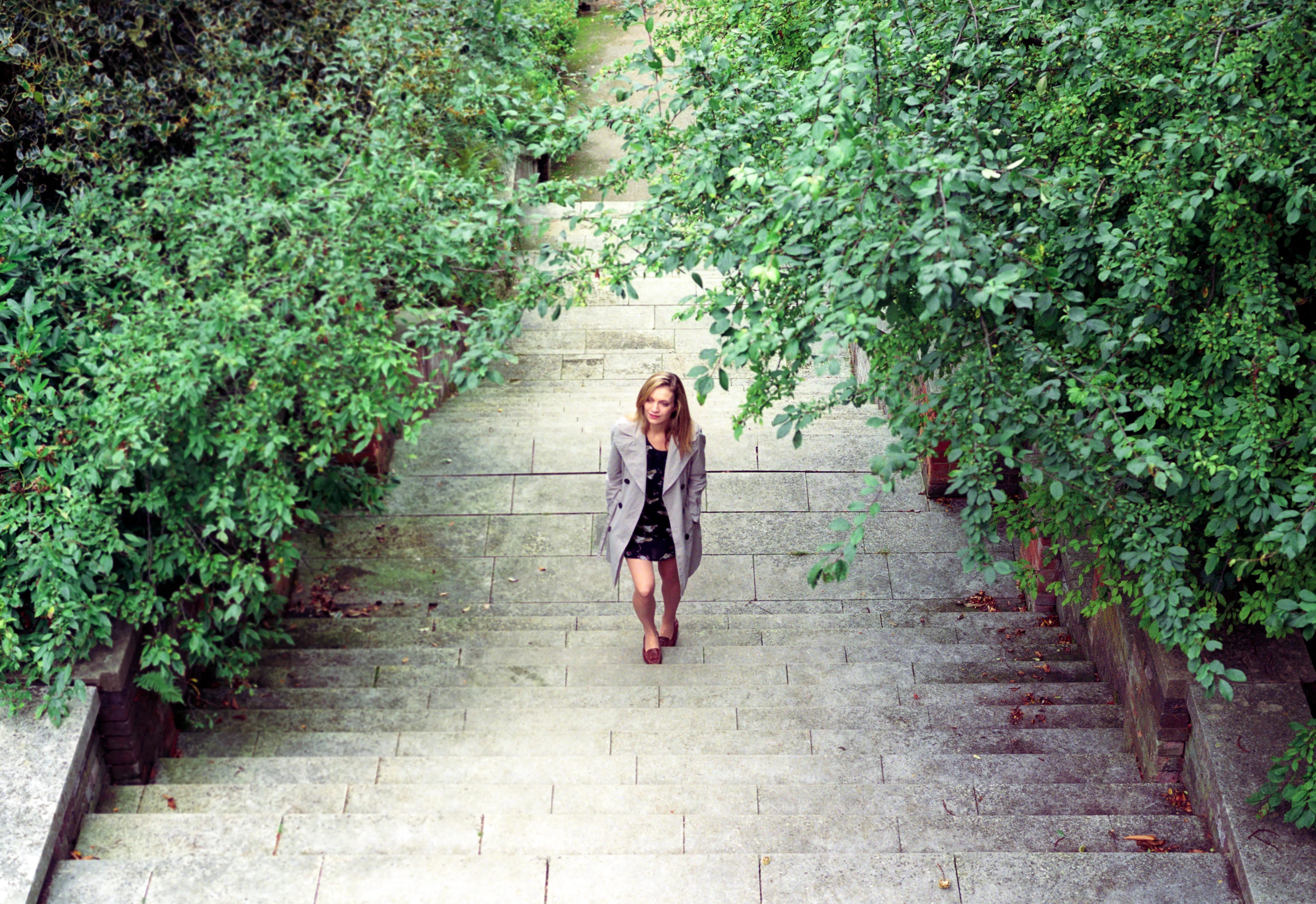 Hannah as a small figure descending a long, overgrown stone staircase.