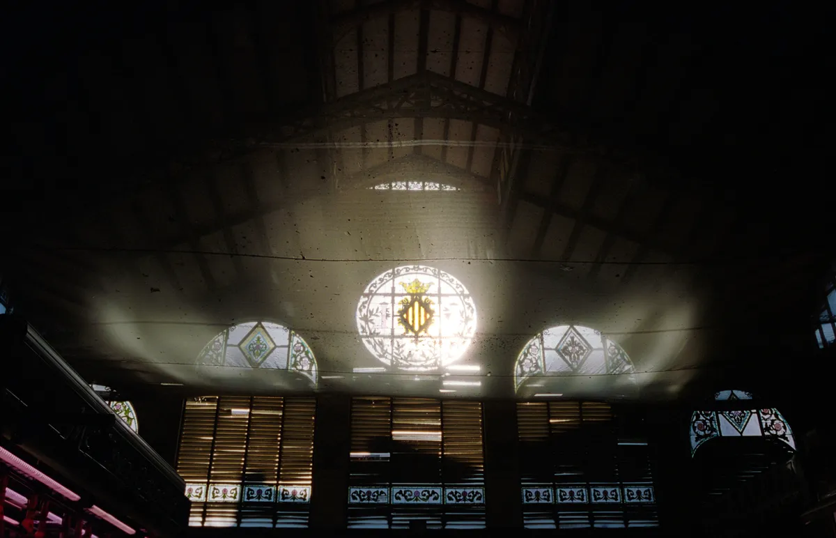 Morning light flaring through the crested round window and louvres of the market's dark roof.