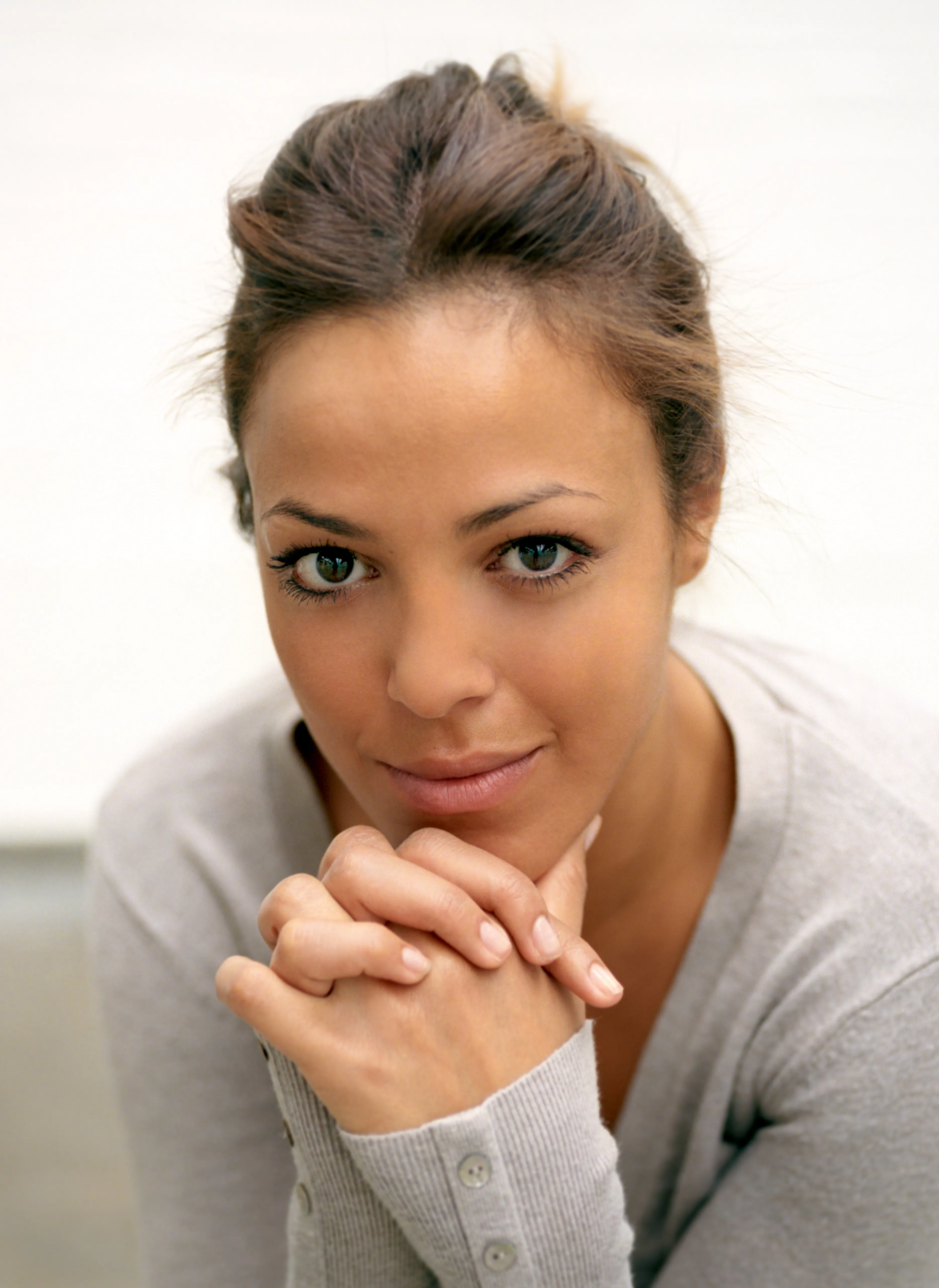 Nawal rests her chin on clasped hands and holds the camera with a steady, direct gaze.