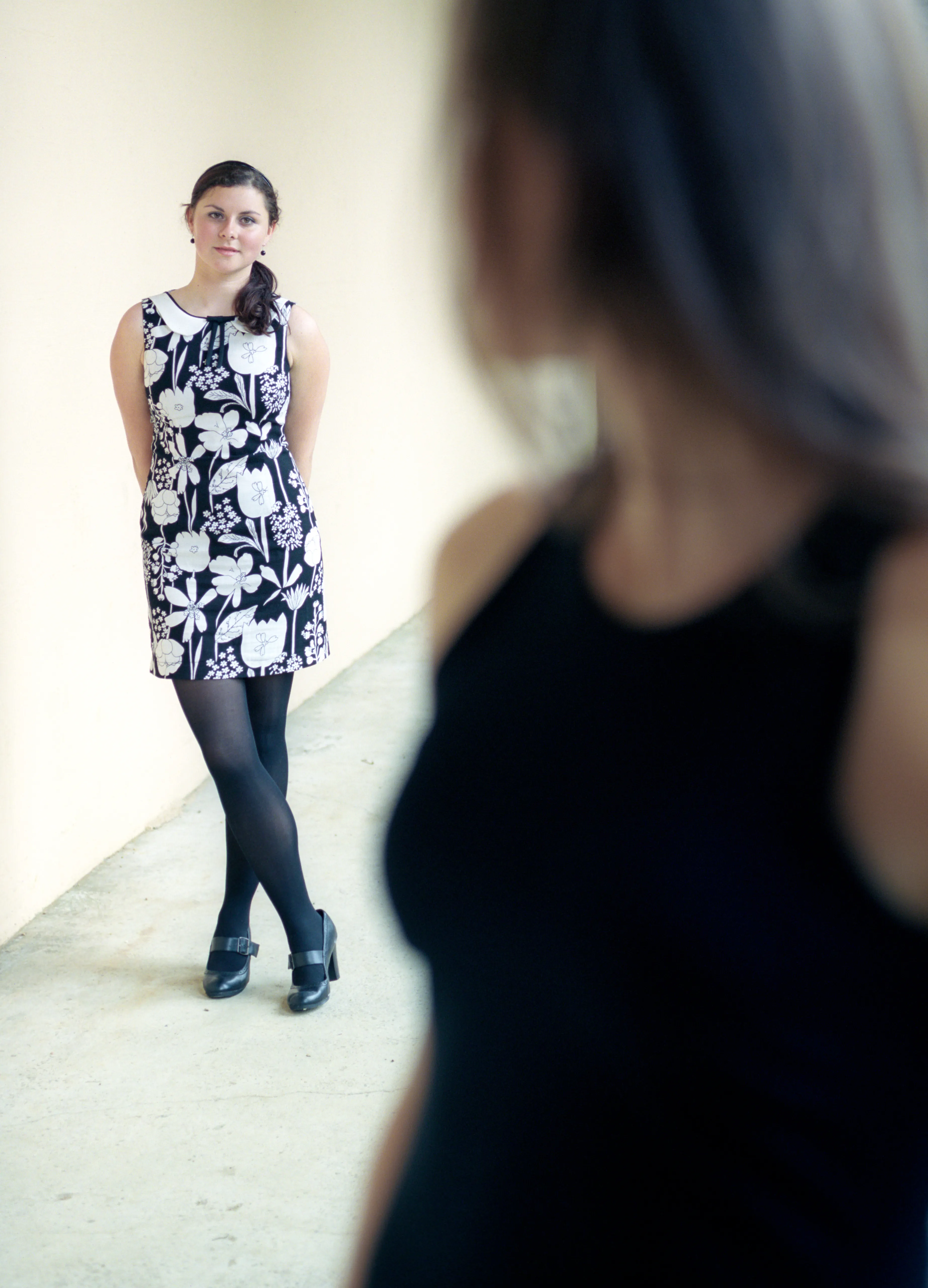 A young woman in a patterned dress walking away along a path, glancing back over her shoulder.