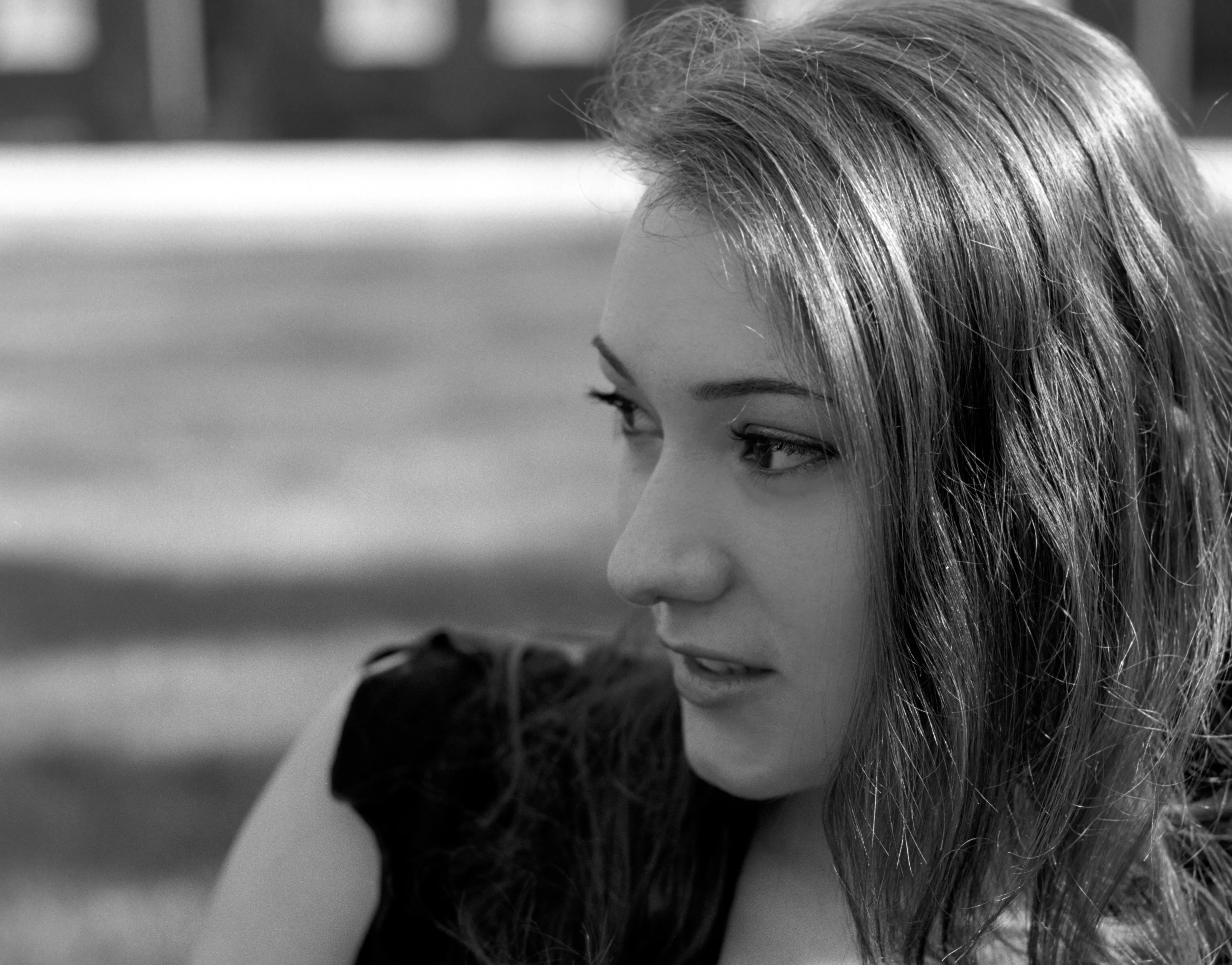 Black-and-white photograph of a young woman with her hair over one shoulder, looking down and to the side.