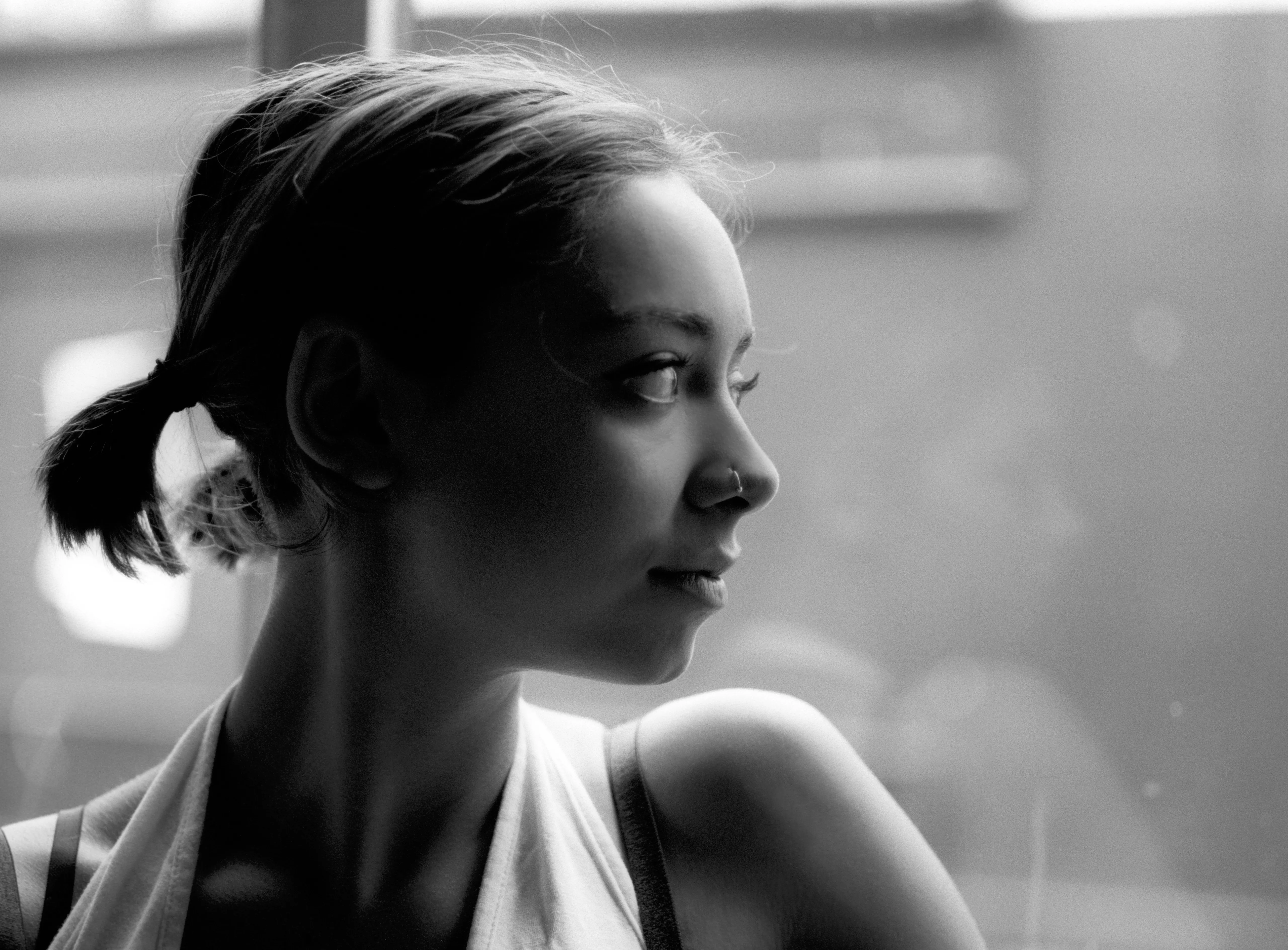 A monochrome profile of Riya looking into the distance, her face softly lit against a hazy background.