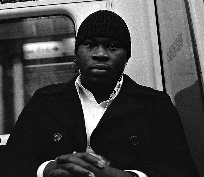 A passenger looking directly into the camera on the London Underground — a sudden, direct gaze.