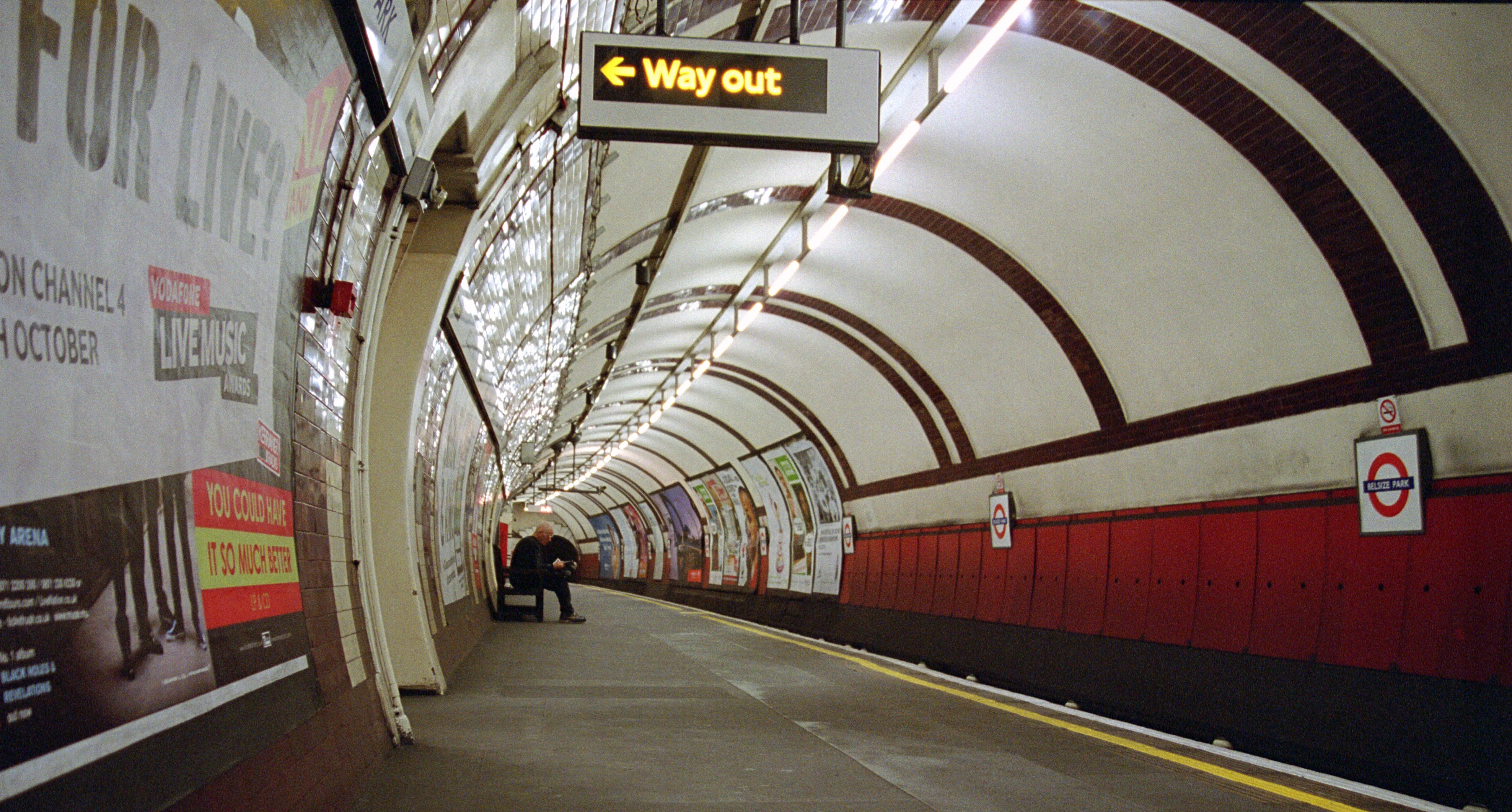 A long London Underground platform, a few passengers strung out along the wait.