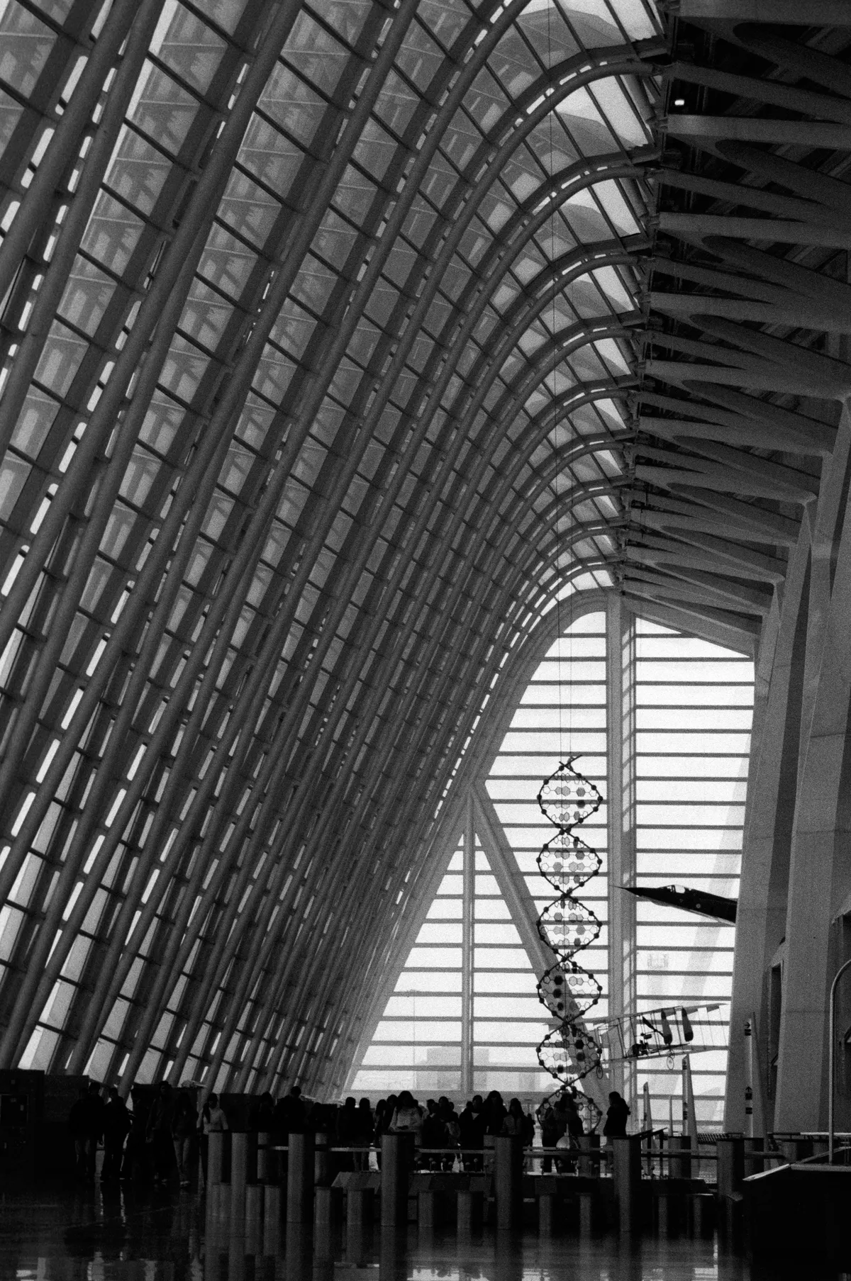 Inside the Science Museum, the DNA sculpture and a suspended aircraft against the sweep of glazing, visitors small below.